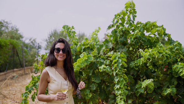 Woman standing in the vineyard holding a glass of white wine
