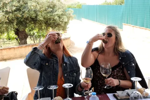Two guests sharing local food and wine at an outdoor tasting table.