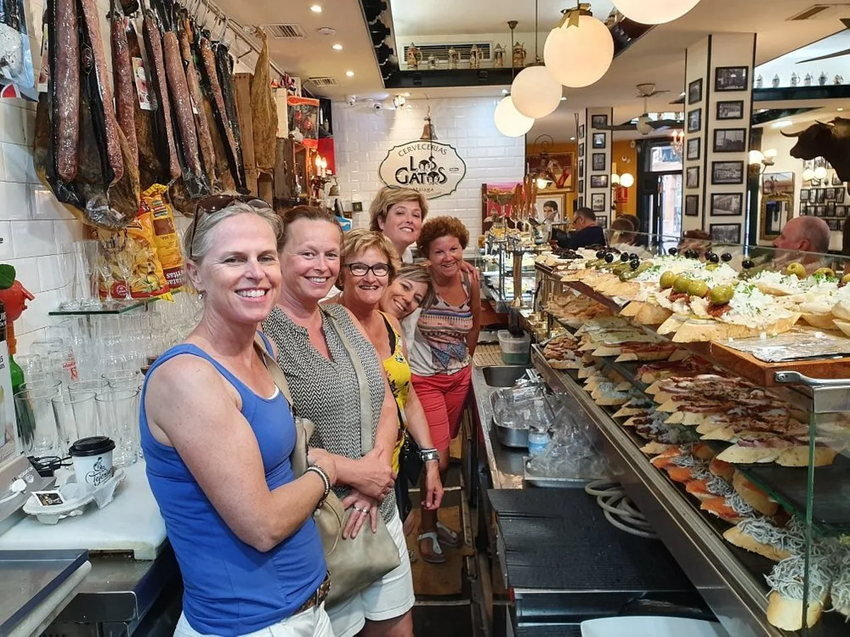 Guests enjoying a tapas route beside a traditional Málaga bar counter