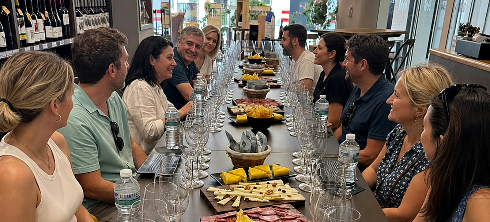 Guests smiling and sharing conversation around the central Málaga tasting table.