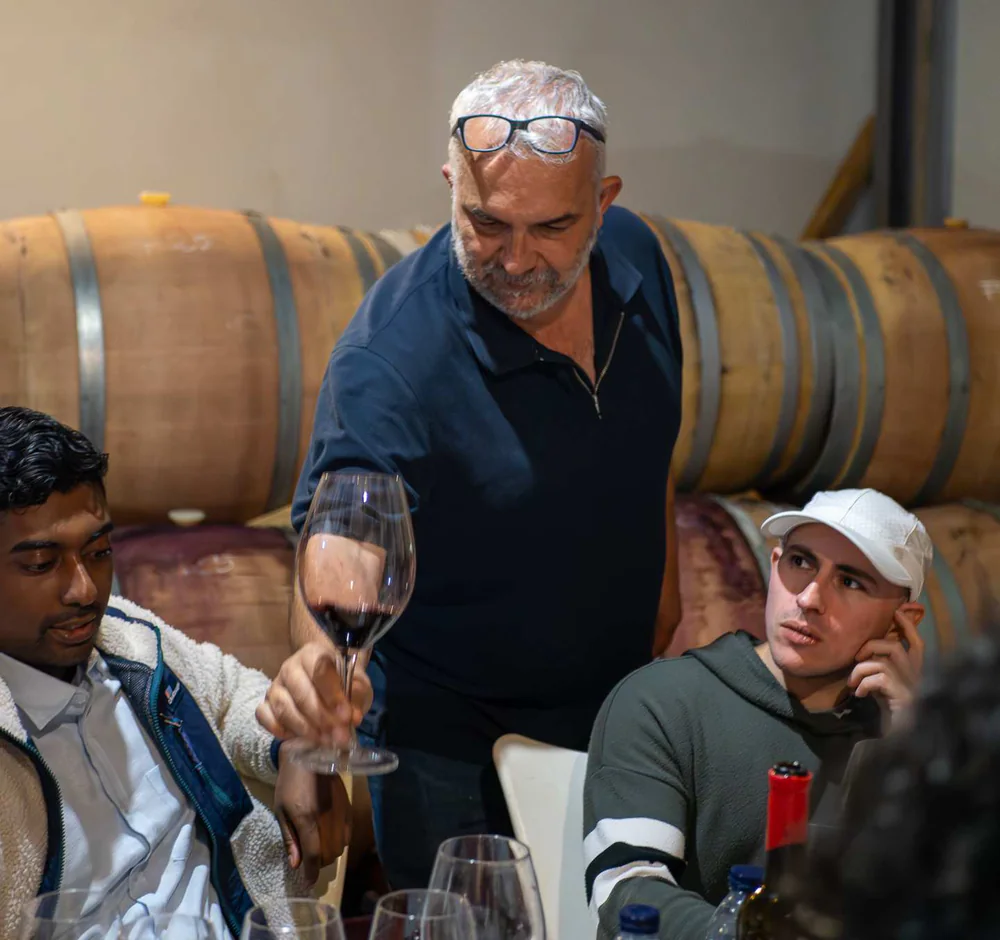 Antonio Mérida presenting a glass of organic wine to guests in the barrel room.