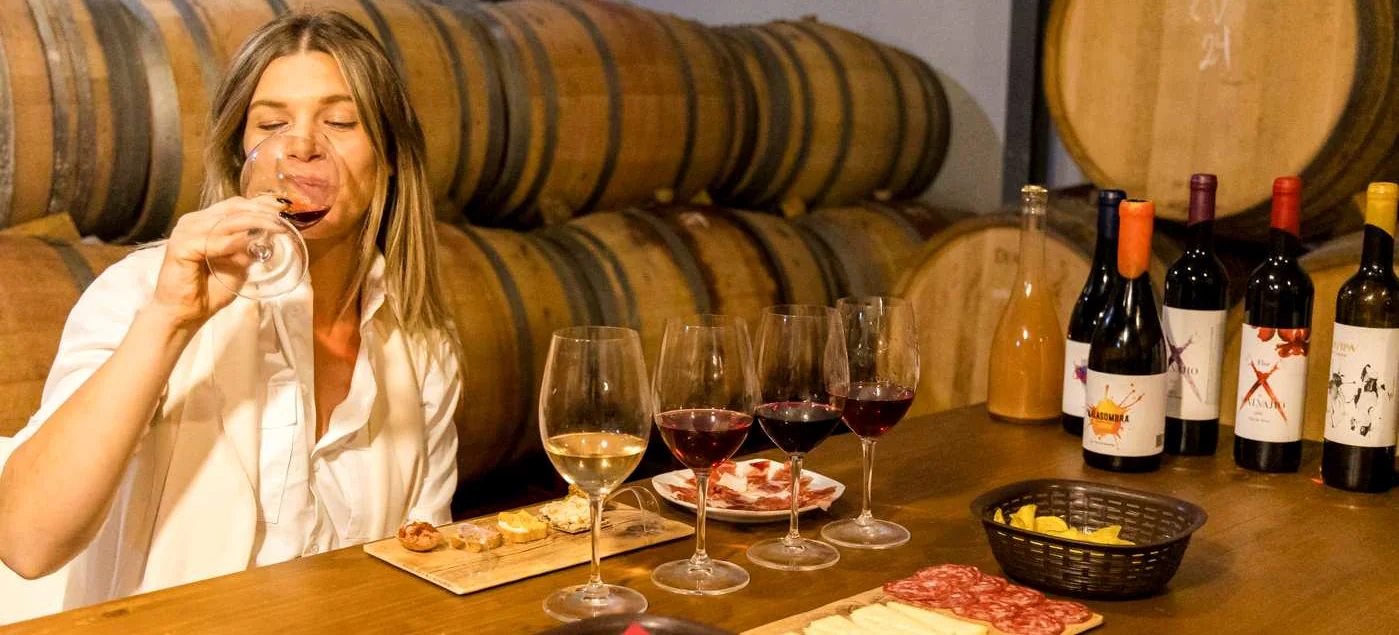 Guest tasting a flight of organic wines beside the barrels in Antonio Mérida’s winery.