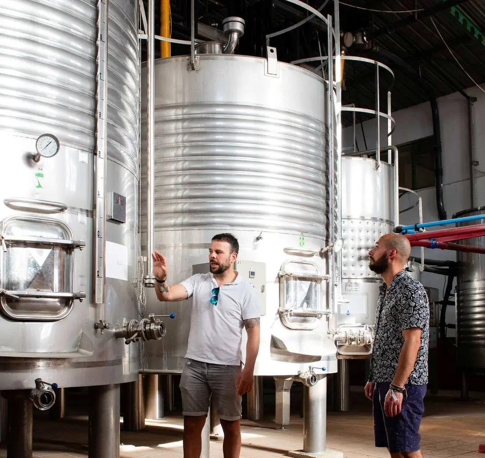 Guests learning about wine production beside stainless-steel tanks.