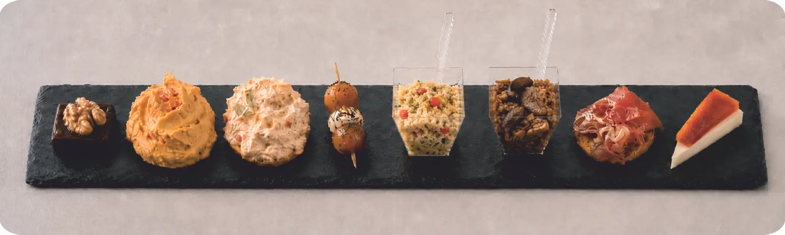 Individual local tapas arranged on a long slate pairing board.