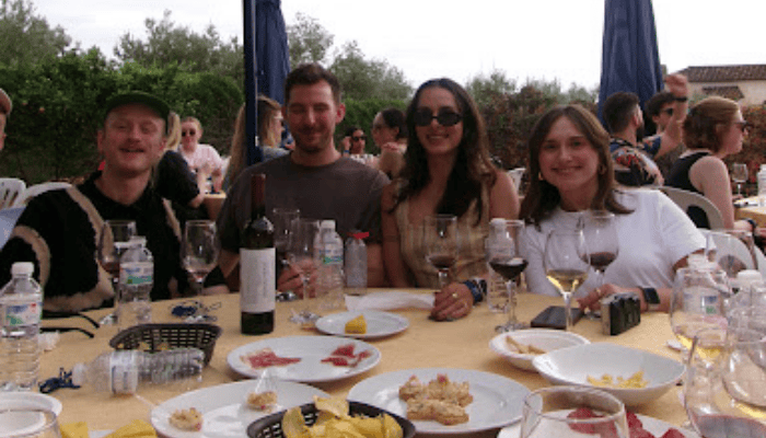 Large group of professionals enjoying a business wine tasting event with local delicacies in a relaxed outdoor setting.