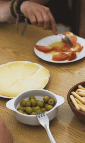 Traditional Spanish tapas with cheese, green olives, breadsticks, and tomato with olive oil